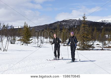 SCANDES, SWEDEN ON APRIL 27. View of two unidentified women cross-country skiing along a trail on April 27, 2013 in the Scandes, Sweden. Track and forest.