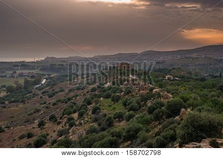 Sunset in Valley of temples in Agrigento in Sicily with clouds and night illumination.