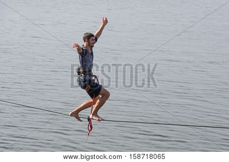 DNEPR UKRAINE - OCTOBER 01 2016:Young rope-walker keeping balance on a rope under Dnepr river in center of the Dnepr city at October 01, 2016