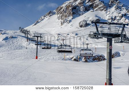 Ski lift in mountains at winter. Alpine winter mountain landscape. French Alps covered with snow in sunny day. Val-d'Isere, Alps, France