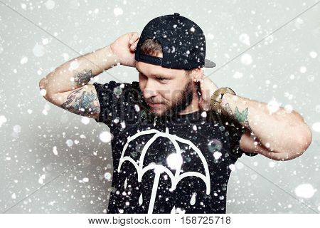 winter christmas people happy concept- Baerded man in black t-shirt on grey background over snow background