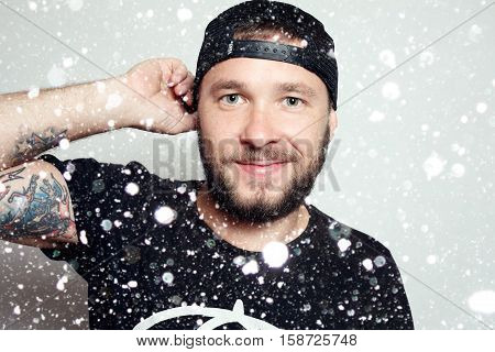 winter christmas people happy concept- Baerded man in black t-shirt on grey background over snow background