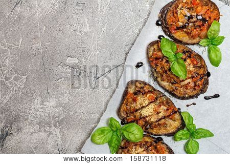 Baked eggplant stuffed with vegetables and cheese with addition aromatic herbs and sauce on paper. Delicious vegetarian dish. top view, sopy space