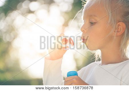 Little girl with soap bubbles in summer