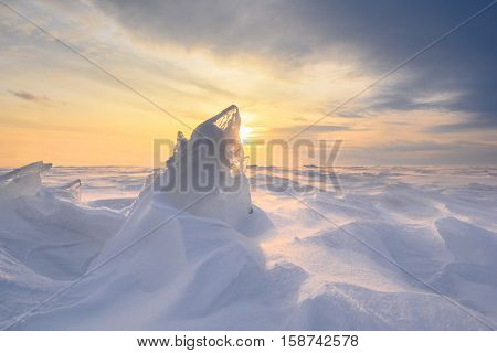 Boundless icy landscape during a snowstorm at sunset in winter.