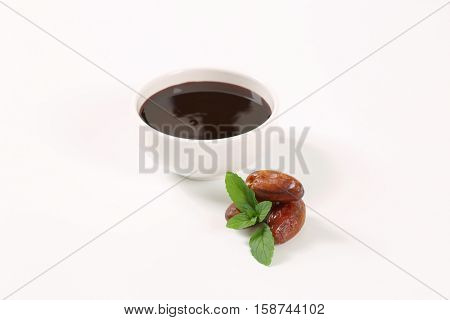 bowl of date syrup with dates on white background