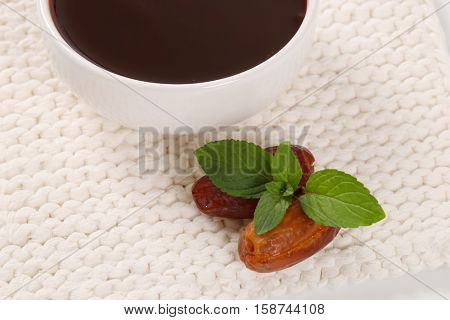bowl of date syrup with dates on white table mat - close up
