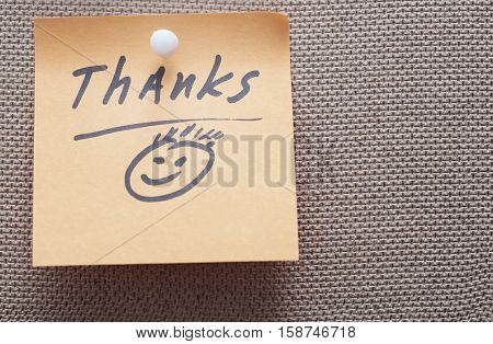 Adhesive note with Thanks text on a bulletin board