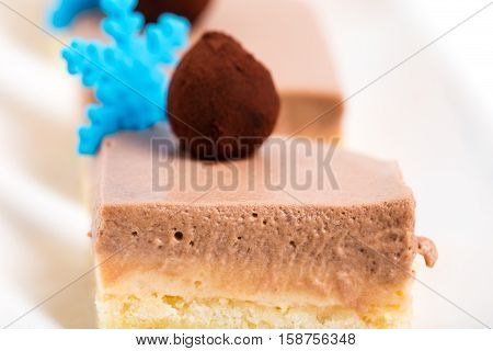 Delicious mousse cakes with chocolate truffles and blue mastic snowflakes. Macro. Photo can be used as a whole background.