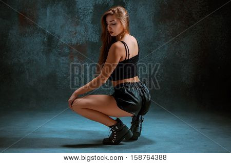 Attractive girl dancing twerk iat the blue studio background