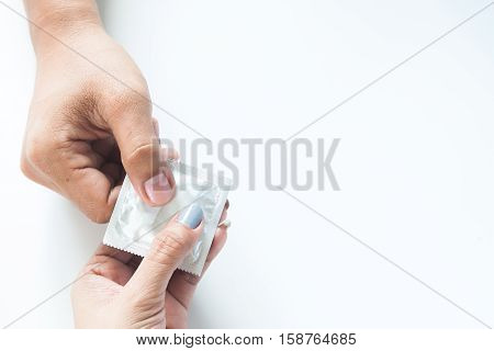 Condom in male hand and female hand give condom safe sex concept on white background