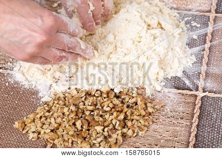 Male hands making dough with walnuts and grated butter on a table as a background.