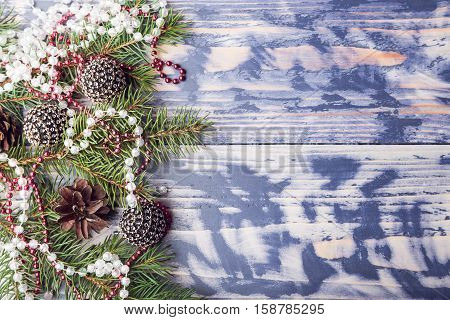 New Year background with pine cones red beads and spruce branches on the bright wooden blue backdrop top view copy space at the right