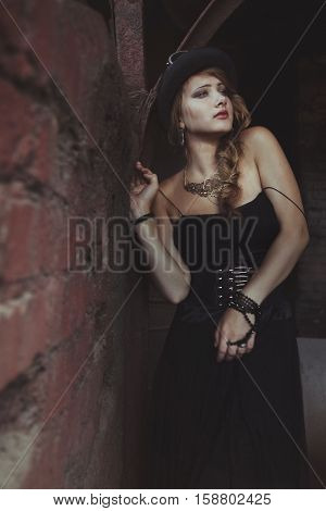 blonde girl in black dress at an old abandoned factory. steampunk