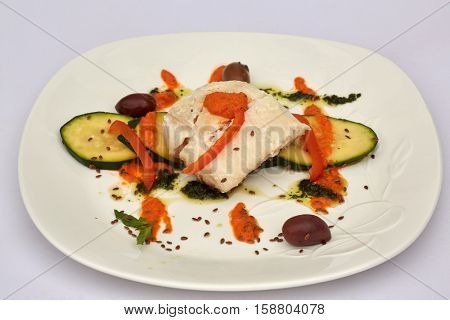 Fish with shredded and sliced vegetables and sauce on plate.