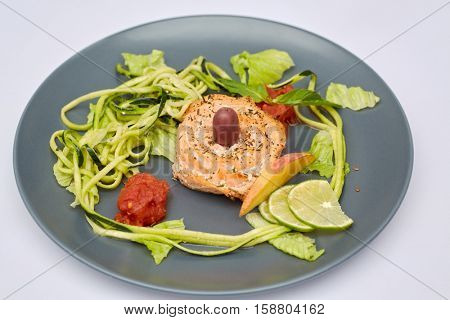 Red fish roll with shredded and sliced vegetables and fruits on plate.
