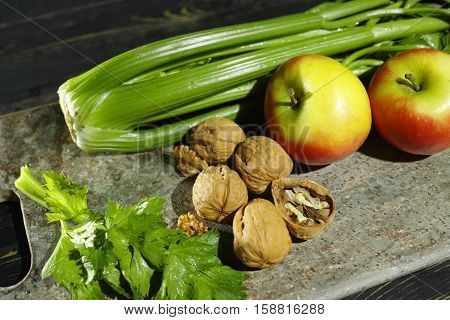 Ingredients for Waldorf salad - celery apples walnotes - fresh and healthy vegetables on granite board.
