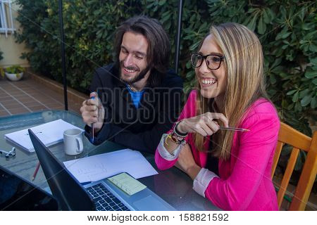 Young businesspeople working with laptop on the terrace of their house. They are two boys and two young girls who are creating a company and are chatting and contributing their ideas.