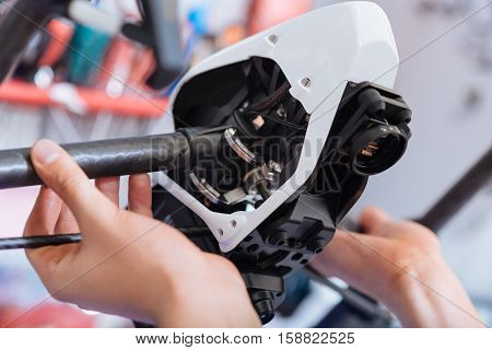Make it work better. Close up of young mans hands putting together drone parts while working and enjoying his hobby in workroom.