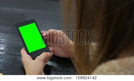 Woman looking at smartphone with green screen. Close up shot of woman's hands with mobile