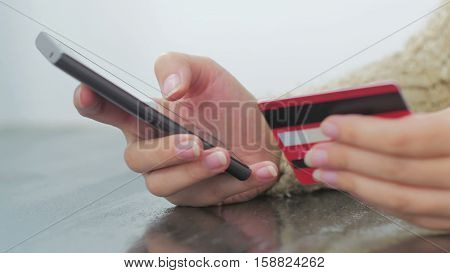 Young woman buying goods from the internet and entering number security code from credit card on smartphone. Online, technology and internet concept