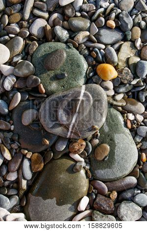 Various size and shape color pebble stones lying one on another with white straight streak line combined of three stones