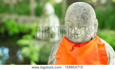 japan travel and buddha statue concept - Close up monk stone statue with red cloth in hasedere temple Kamamura Japan