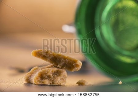 Close up detail of marijuana extraction concentrate aka wax crumble with green glass jar