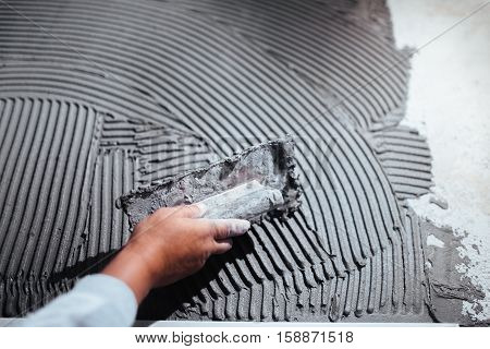 Close Up Of Worker Hand Plastering A Wall, Adding Adhesive With Comb Trowel
