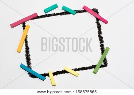 The black frame on a white background, painted wax crayons on the edges of multicolored chalk. Children's creativity. Colorful chalk. Space for text, letters, words. Education, to develop the child.