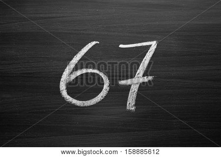 number sixty seven enumeration written with a chalk on the blackboard