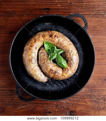 homemade sausages in a pan on a wooden background