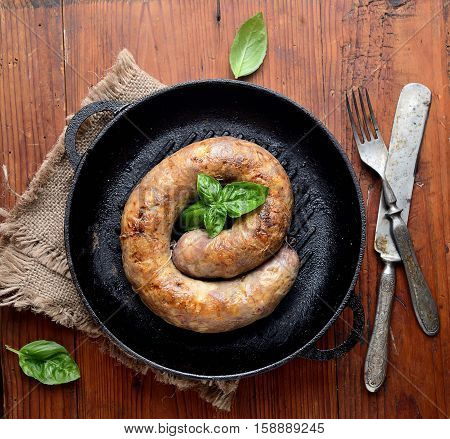 homemade sausages in a pan on a wooden background
