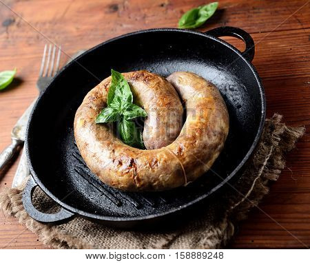 homemade sausages in a pan on a wooden background
