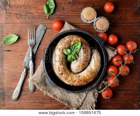 homemade sausages in a pan on a wooden background