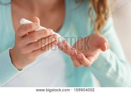 Woman using lancelet on finger
