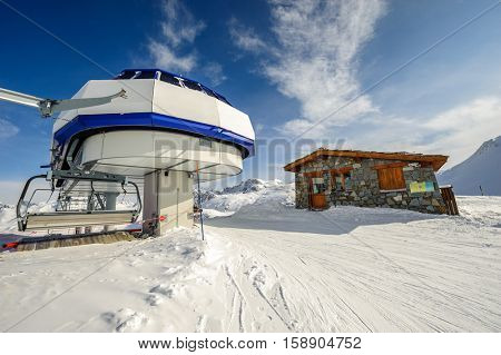 Ski lift station in mountains at winter. Alpine winter mountain landscape. French Alps covered with snow in sunny day. Val-d'Isere, Alps, France