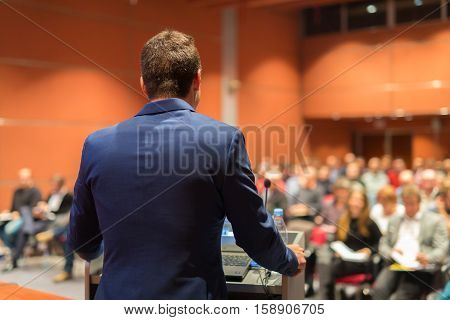 Speaker giving a talk on corporate Business Conference. Audience at the conference hall. Business and Entrepreneurship event.