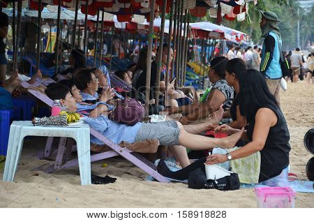 Tourists Receive A Massage On Pataya Beach From Thai Women