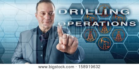 Smiling male industrial manager pressing DRILLING OPERATIONS on a virtual control screen. Petroleum industry concept and fossil fuel metaphor for drilling technology derrick pumpjack and oil wells.