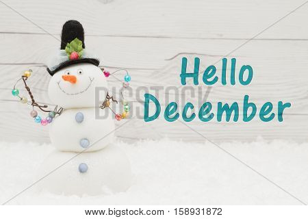 Hello December message Some snow and a snowman on weathered wood with text Hello December