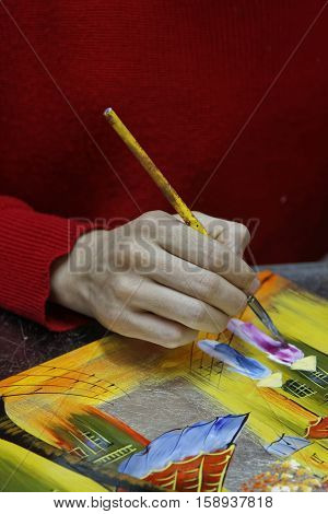 HANOI VIETNAM October 30 2016 : Unidentified artist paints in a workshop of lacquer of Hanoi. Lacquerware are objects decoratively covered with lacquer mostly from East Asian cultures.