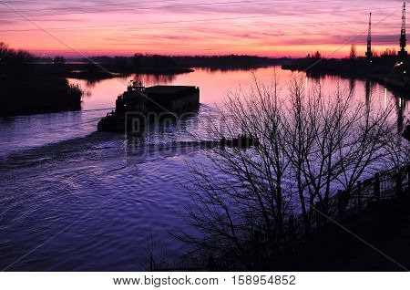 Beautiful Colorful Dusk On A River With Silhouettes Of Boat And Barge.