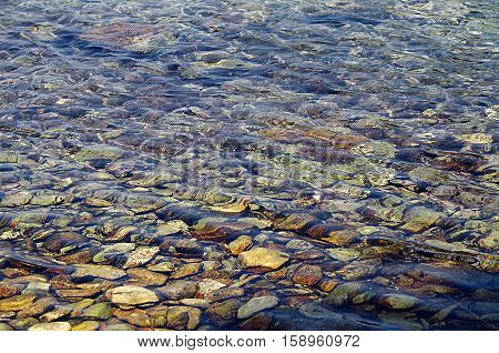 A rocky beach seen through the crystal clear waters of the sea.
