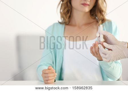 Doctor using lancelet on woman finger