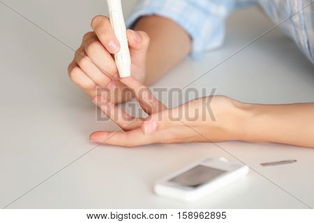 Woman using lancelet on finger