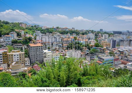 View of typical residential houses in the green area of Santa Teresa, blue sky and white clouds at hot, sunny day in Rio de Janeiro, Brazil