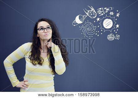 Young thinkful woman on blue gray background with universum icons. Confusion.