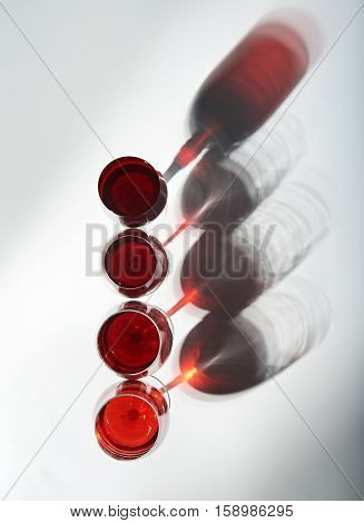 shadows from red wine glasses on white background view from top