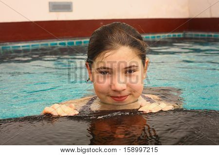 teen girl close up portrait in open air swimming pool in thailand condominium